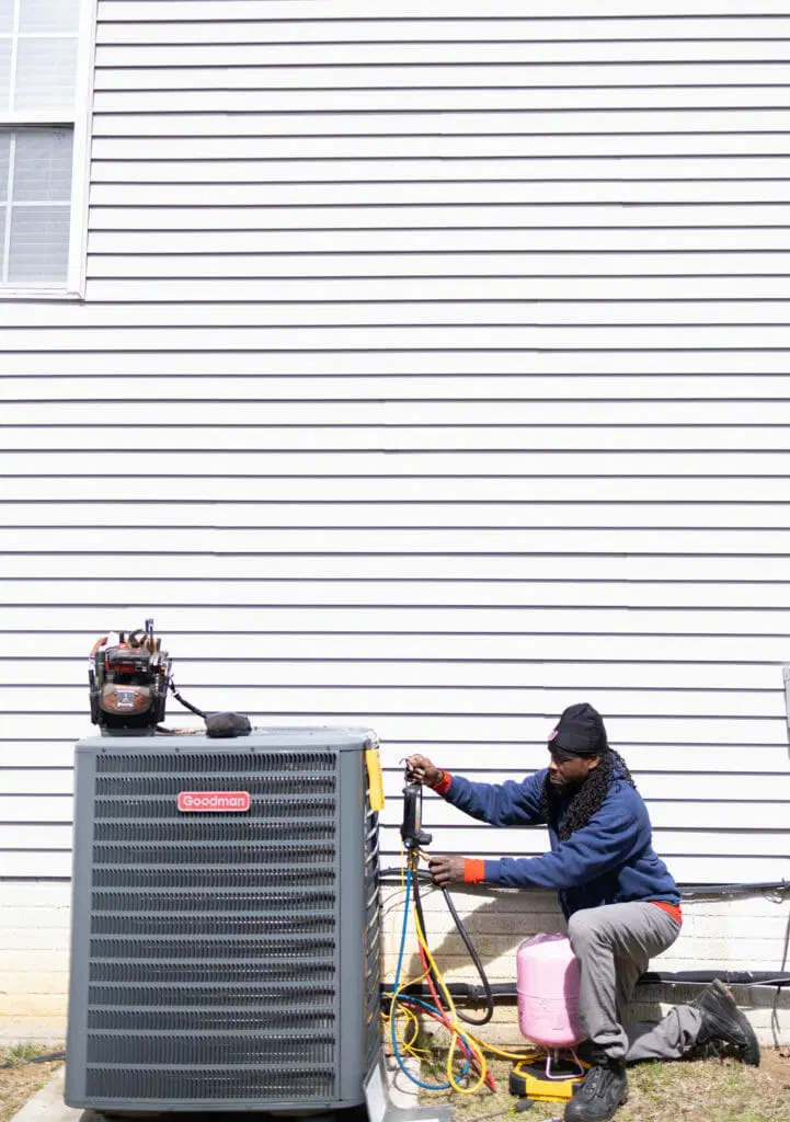 HVAC technician inspecting furnace or air handler in residential utility room professional heating system service