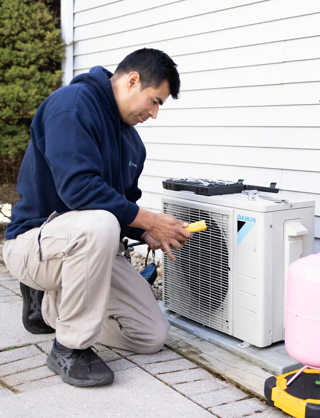 HVAC technician inspecting outdoor mini split air conditioning unit with tools residential AC service