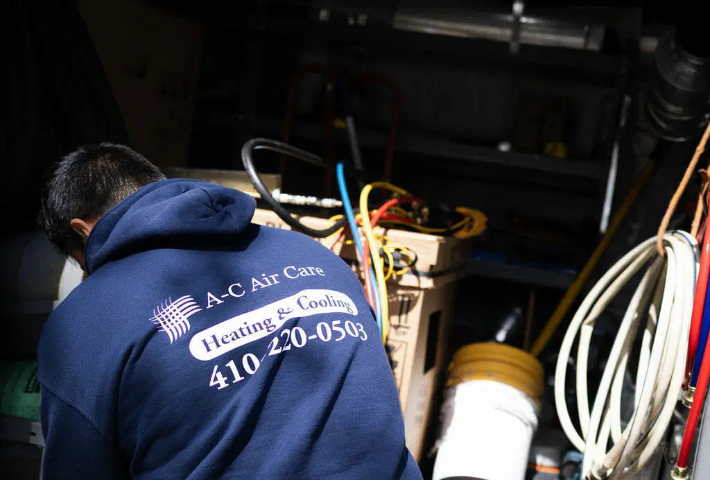 A‑C Air Care HVAC technician working with tools and equipment in service van during AC repair